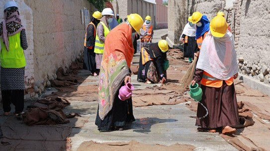 Women pour water on burlap clothes for concrete curing at  Kariz Kabeer street in Gozar