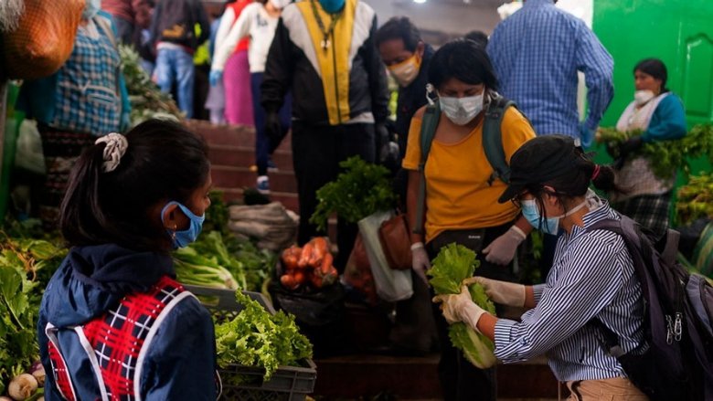 Gente comprando hortalizas en un mercado