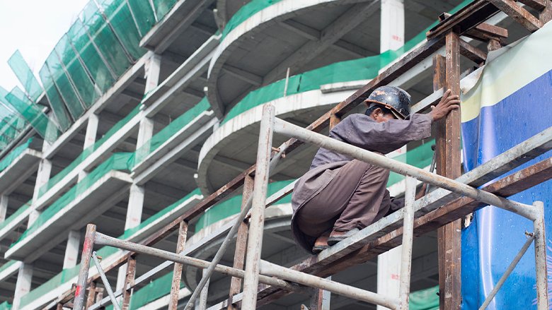 A construction worker holds onto a vertical beam at a building site in Cambodia