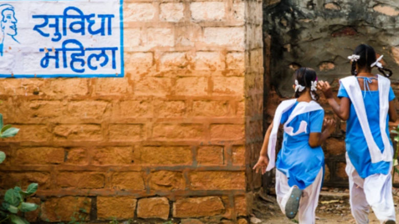 Girls running toward toilet facilities in a rural school in India