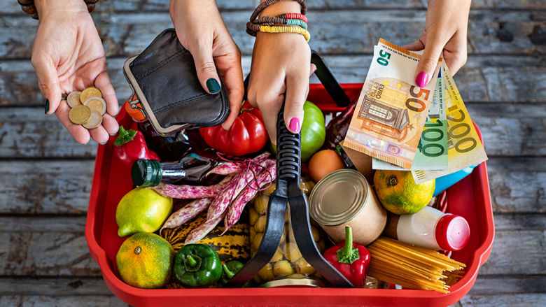 Hands reaching into shopping basket with money and purse