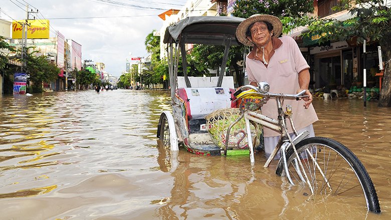 Man drives rickshaw through flooded street