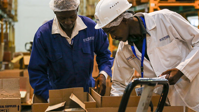 Shopkeepers at the Kenya Medical Supplies Authority go through a purchase list from a health center, pick the supplies and pack them into boxes.