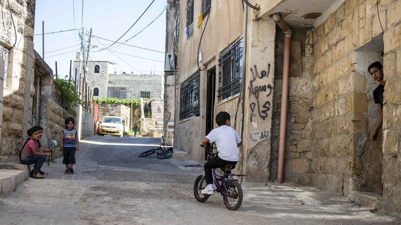 A kid ridding a bicycle in front of a house in Qalqiliah City, West ƵAPP. 