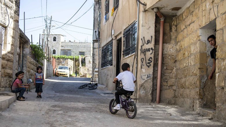 طفل يركب دراجته أمام منزل في مدينة قلقيلية بالضفة الغربية. 