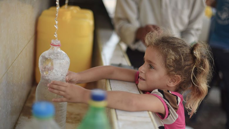 A Palestinian girl fills a bottle with clean water from a public tap.