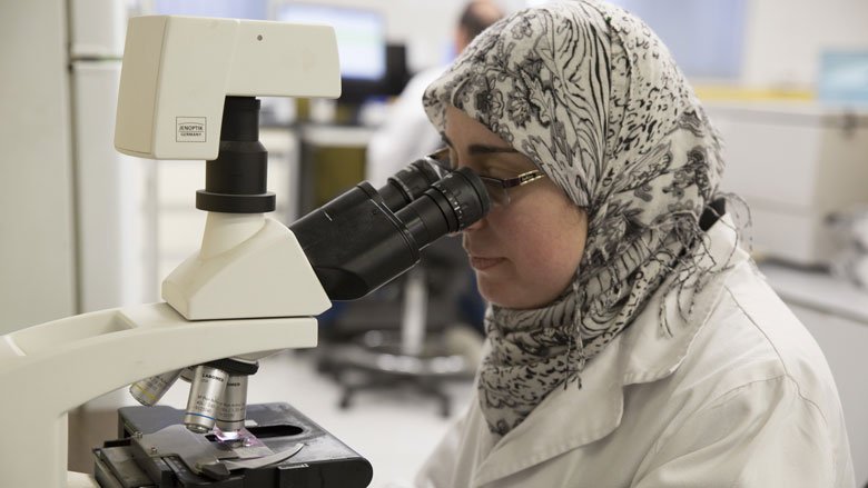 طبيبة فلسطينية تفحص عينة امام المجهر. 