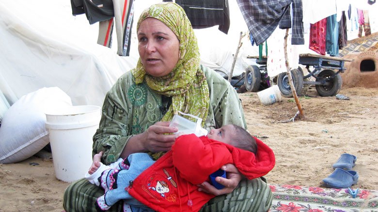A Palestinian woman feeds her baby in a refugee camp