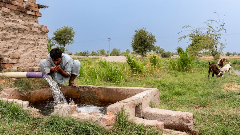 A Pakistan man drinks clean water from a source thanks to a World Bank supported project in his village