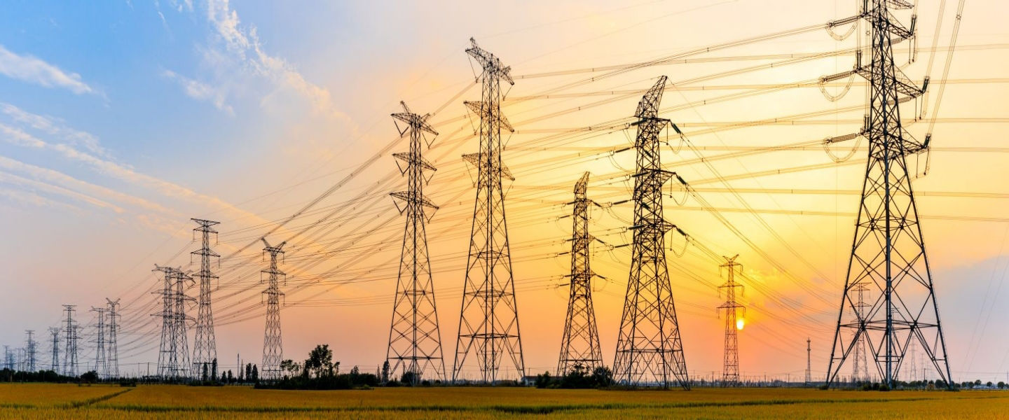 Power lines against a bright orange sunset
