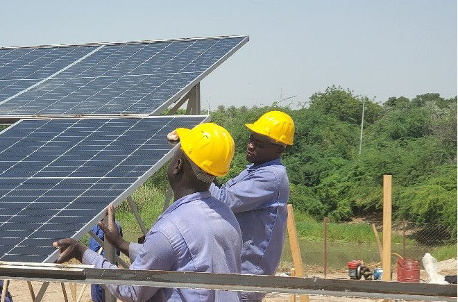 Workers in Chad install solar panels to provide energy to water pumps.