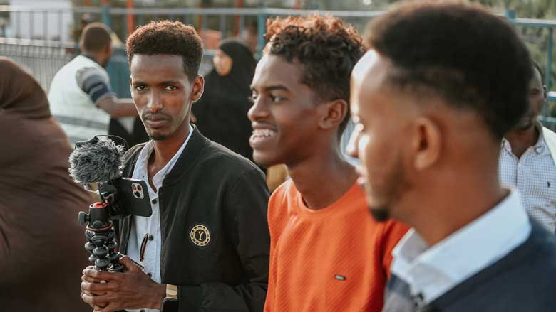 A young Somali man holding a tripod with his phone. Photo: Mukhtar Nuur