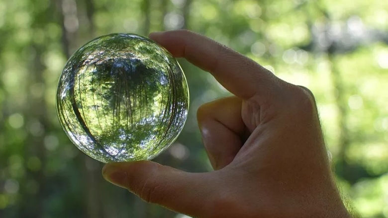  a hand holding a transparent ball green background 