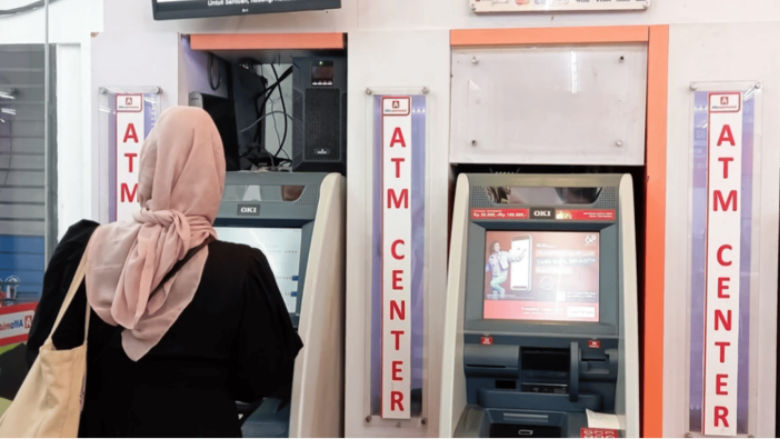 A woman seen from behind withdrawing money from an automated teller machine in Jakarta, Indonesia. 