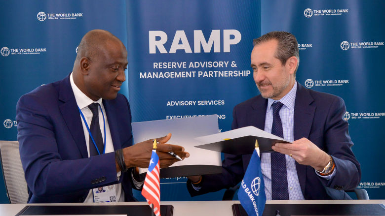 Central Bank Governor Henry F. Saamoi and World Bank VP & Treasurer Jorge Familiar shake hands and hold contracts